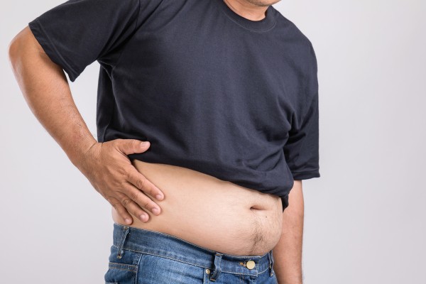 Mann mit Fettleber durch ungesunde Ernährung oder andere Faktoren hält sich den Bauch.