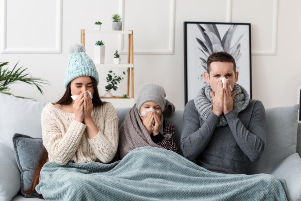Familie mit Grippe putzt sich auf Couch die Nase