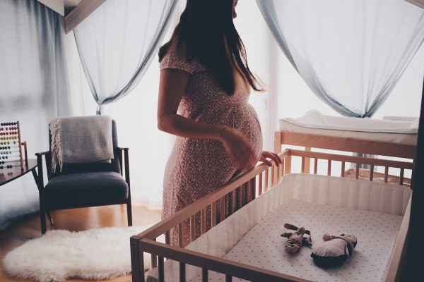 Frau mit Schwangerschaftsdepression vor Babybett