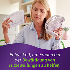 Frau mit Hitzewallung fächelt sich mit einem Ventilator und einem Papier Luft zu.