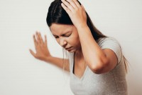 Frau, die unter vestibulärer Migräne leidet, hält sich den schmerzenden Kopf.