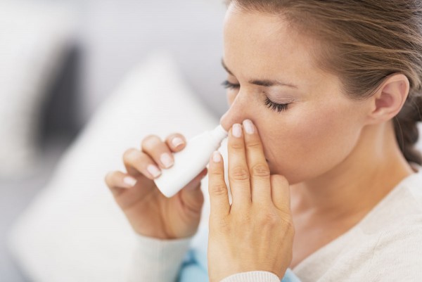 Frau versucht mit Nasenspray Erkältungssymptome zu lindern