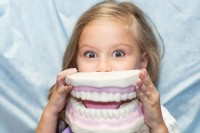 Kind spaßt mit riesigem Gebiss herum, das Zahngesundheit und Karies veranschaulicht