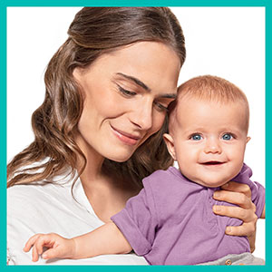 Glückliche Mutter hält ihr strahlendes Baby im Arm.