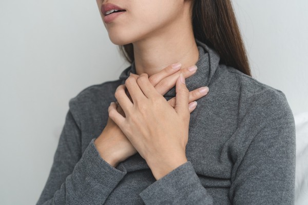 Frau mit Unterfunktion durch Hashimoto hält sich Schilddrüse