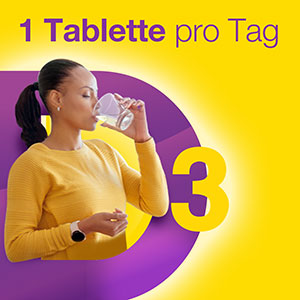 Frau trinkt Wasser und nimmt eine Vigantolvit Tablette, um die tägliche Dosis Vitamin D3 zu erhalten.
