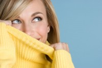 Frau mit gepflegter Haut versteckt Akne im Gesicht unterm Pullover