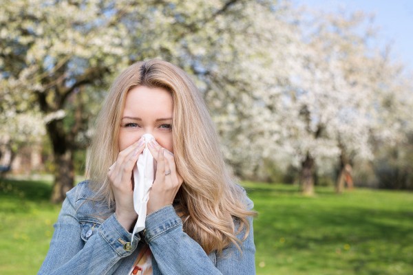 Frau putzt sich bei Heuschnupfen und Allergie im Freien die Nase.