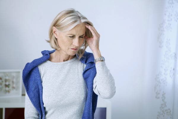 Frau, die unter einer der Kopfschmerzenarten leidet, hält sich den schmerzenden Kopf.