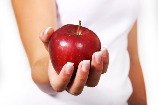 Frau mit rotem Apfel in der Hand, der gesundes Abnehmen symbolisiert