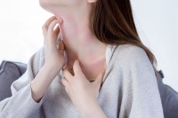 Frau kratzt sich aufgrund einer Nickelallergie am Hals
