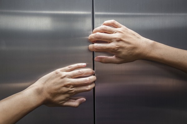 Hände versuchen bei Angst im Aufzug eine Tür zu öffnen