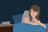 Eine Frau, die nicht einschlafen kann und nachts auf die Uhrzeit schaut.